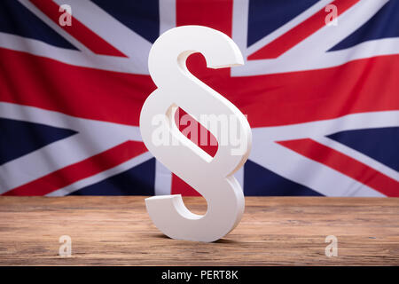 Paragraphe blanc symbole sur un bureau en bois en face du drapeau de l'Angleterre Banque D'Images