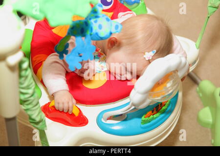 Bébé fille 8 mois s'endort sur son bébé bouncer tout en jouant. Banque D'Images