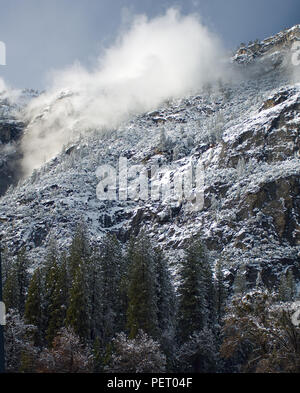 Vent souffle un nuage de neige à partir de la parois de granit entourant la vallée de Yosemite National Park. Banque D'Images