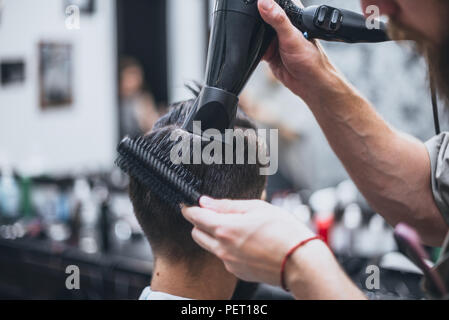 Obtenir la forme parfaite. Close-up vue latérale du jeune homme barbu se coupe de barbe par coiffure à barbershop Banque D'Images