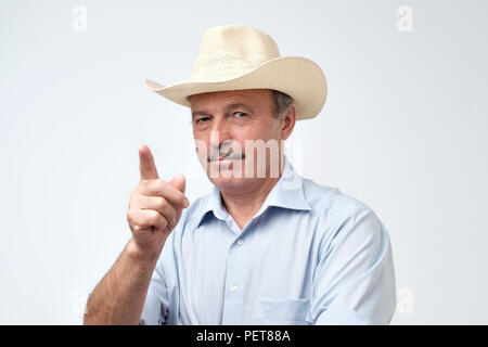 Serious mature man in cowboy hat montrant l'index vers le haut, donner des conseils ou recommandation. Écouter l'expérience de l'ancienne génération Banque D'Images