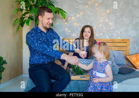 Heureux les jeunes parents et leur petite fille jouant togerher à la maison. La famille, de l'enfance et des loisirs concept Banque D'Images