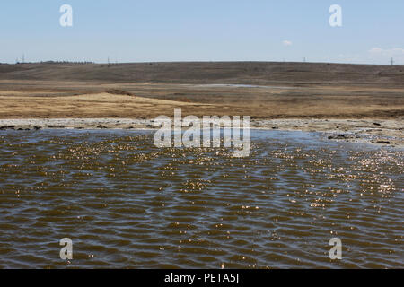 Un petit lac boueux avec de l'eau jaune situé à côté de la boue froide, qui est créé à la suite de la libération de gaz à partir de l'interio Banque D'Images