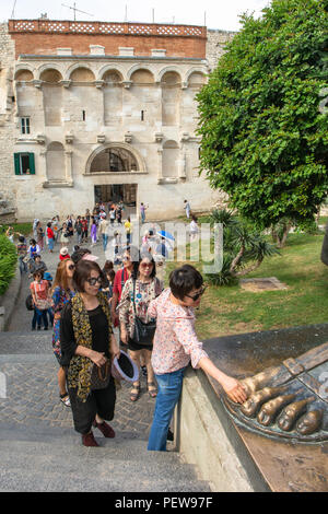 Split, Croatie. Asian female tourist est de frotter le pied de la statue de Grgur Ninski, l'Évêque Grégoire de Nin - il est dit pour porter chance. Banque D'Images