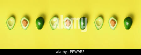 Avocat biologique avec la semence, avocat à moitiés fruits sur fond jaune. Vue d'en haut. Bannière, modèle homogène. Pop art design créatif, l'alimentation d'été Banque D'Images