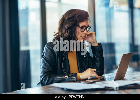 Portrait of woman working on laptop computer in office. Asian business woman in casuals travaillant au bureau. Banque D'Images