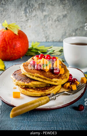 Petit-déjeuner d'automne idée, potiron crêpes, avec des tranches de citrouille, le sirop d'érable ou miel, canneberge, sur un fond de béton bleu, l'espace pour le texte Banque D'Images