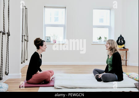 Deux femmes assis les jambes croisées en face de l'autre dans un studio d'exercice Banque D'Images