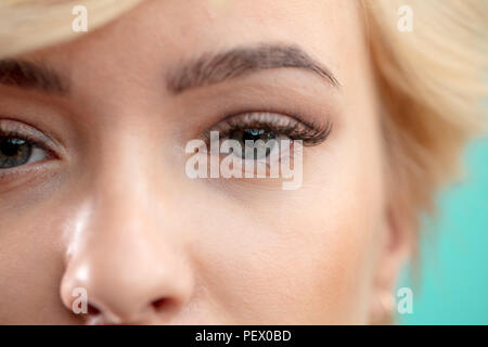 Close up portrait photo d'une belle femme uoung avec de longs cils de curling. studio shot isolé sur fond bleu.la peau parfaite et cils denses conc Banque D'Images