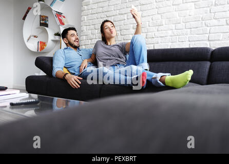 Young Couple On Sofa At Home Selfies Banque D'Images