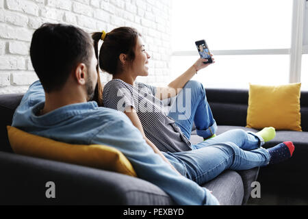 Young Couple On Sofa At Home Selfies Banque D'Images