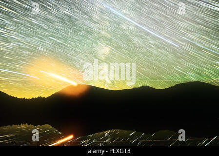 Star trails de voie lactée et définition planète rouge mars. Les étoiles se reflètent dans le lac alpin en face de la montagne. Banque D'Images