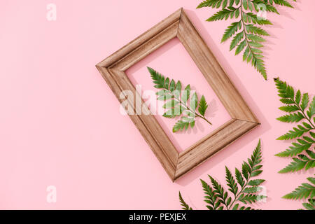 Minimaliste à la main, décor intérieur botanique tropical vert feuilles dans des cadres en bois accroché sur fond rose Banque D'Images