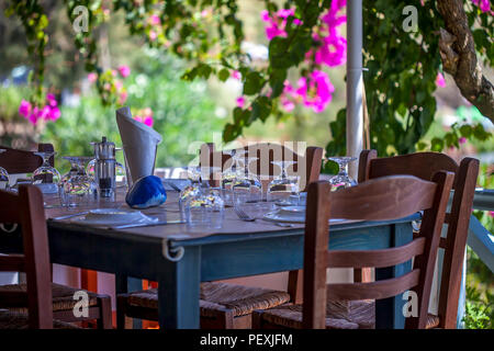 Le tableau mis en place dans le jardin. Table de jardin en plein air avec des fleurs roses en arrière-plan.. Le point de droit. Banque D'Images