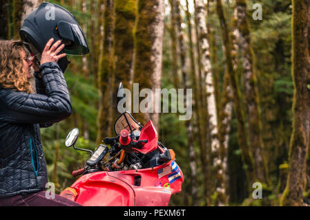 Femme sur le port du casque de moto au décollage en forêt Banque D'Images