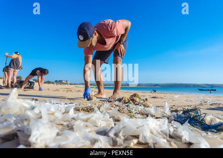 Man picking up trash à plage, Jimbaran, Bali, Indonésie Banque D'Images