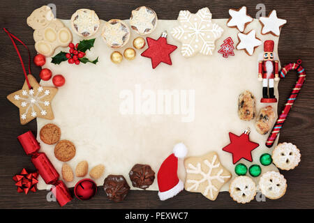 Fond de Noël frontière avec symboles de fête décorations de l'arbre, biscuits, gâteaux, les noix, le chocolat dans le papier d'aluminium et de l'hiver sur le papier parchemin sur la flore Banque D'Images