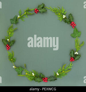 Couronne de Noël et d'hiver naturelles avec guirlande de feuilles, branches de cyprès cèdre des baies de houx, de lierre et de gui sur fond vert tacheté. Savoirs traditionnels Banque D'Images