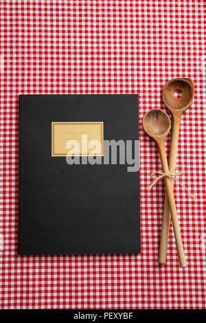 Livre de recettes de cuisine. Ordinateur portable et d''ustensiles de cuisine en bois sur l'nappe rouge, vue du dessus Banque D'Images