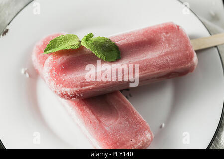 Blueberry la crème glacée ou les popsicles avec feuilles de menthe verte sur la plaque blanche. Couleur rustique de style. Le jus de fruits surgelé dans un style vintage. Haut Voir photo. Banque D'Images