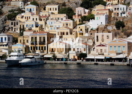 La Grèce, l'île de Symi. Bateaux amarrés dans le port en face de vieux manoirs néo classique. Banque D'Images