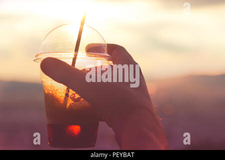 Mans hand holding café glacé contre les rues de la ville en arrière-plan Banque D'Images
