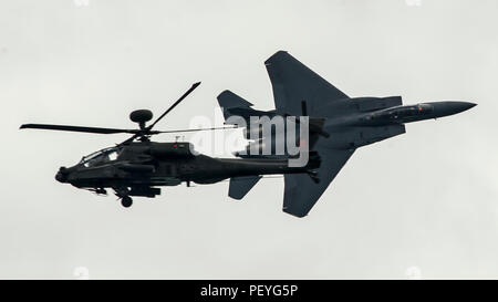 Un F-15SG Strike Eagle de l'armée de l'air de Singapour survole un AH-64D Apache Longbow de l'armée de Singapour lors d'une démonstration aérienne au salon aéronautique international de Singapour à l'aéroport international de Changi le 18 février 2016. Le F-15SG est un chasseur multirôle bimoteur tandis que l'AH-64D est un hélicoptère d'attaque bimoteur. Le survol démontre l'interopérabilité, la capacité de combat aérien et l'entraînement coopératif entre Singapour et les forces militaires américaines, favorisant la sécurité régionale et la compétence opérationnelle. Banque D'Images