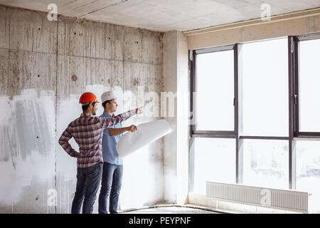 Architector parle avec l'investisseur et dirigée vers l'extérieur, dans l'immeuble. Vue latérale photo.Les personnes cherchant à l'avenir. Perspectives d'avenir Banque D'Images