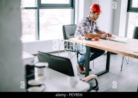 Ingénieur sérieux est concentré sur des formalités administratives de travail. Vue latérale photo. avant-plan flou Banque D'Images
