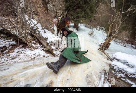 Beijing, Chine. 18 août 2018. Yelixat médecin et son cheval passent par une pente couverte de glace au cours d'un service médical voyage autour d'une zone pastorale dans le comté de la Tekes Préfecture autonome kazakh d'Ili, nord-ouest de la Chine, la Région autonome du Xinjiang Uygur, 21 Décembre, 2017. Chine marquera sa première journée des travailleurs médicaux le 26 août 2008 Credit : Xinhua/Alamy Live News Banque D'Images