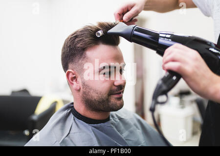 Coiffure blow séchant ses cheveux du client. Banque D'Images