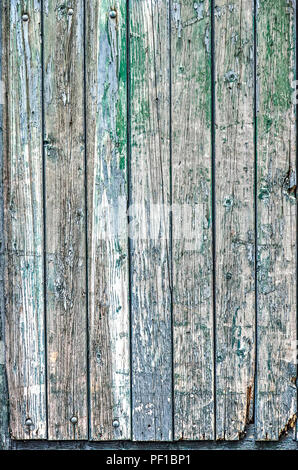 Partie d'une porte en bois avec des planches verticales et de l'écaillage de la peinture dans les tons de vert, bleu, blanc et marron Banque D'Images