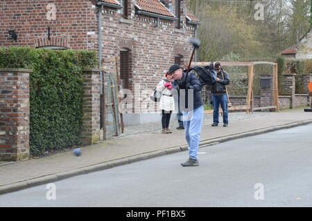 Aumônier de l'armée américaine Lieutenant-colonel William Sager affecté à la garnison de l'armée américaine Benelux, suit la trajectoire de son 'chôlette" au cours de la fête traditionnelle de la ville de Chièvres, Belgique, le 10 février 2016. Le présent rapport annuel de golf-like, cité médiévale de sport "crossage,' a lieu le jour après MardiGras. Une balle d'entraînement joueurs chêne, appelé un "chôlette" (prononcé : show-let), avec un club en bois, ou "rabot" (prononcé : rah-bo), en fûts métalliques fixés autour de la ville. À chaque fois qu'un joueur est prêt à balancer, il crie : "Chôlette." (U.S. Photo de l'armée par Visual Spécialiste de l'information Pascal Demeuldre/libérés) Banque D'Images