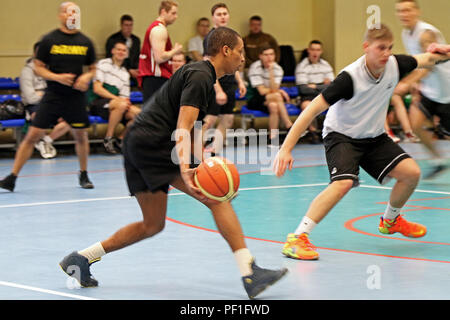 La CPS. Darron Harris (à gauche), un fantassin tir indirect affectés au siège des troupes et de l'Administration centrale, 3e Escadron, 2e régiment de cavalerie, se déplace vers le bas la cour tout en jouant dans un tournoi de basket-ball contre des soldats lettons, le 26 février, dans la région de Jugla, la Lettonie. La troupe de cavalerie et partenaires lettons ont eu l'occasion de jouer dans le tournoi de basket-ball comme une pause dans leur horaire d'entraînement à l'appui de l'opération Atlantic résoudre, une démonstration de multinationales des États-Unis, la poursuite d'engagement à la sécurité collective des alliés de l'Organisation du Traité de l'Atlantique Nord. (U.S. Photo de l'armée par le Sgt. Paig Banque D'Images