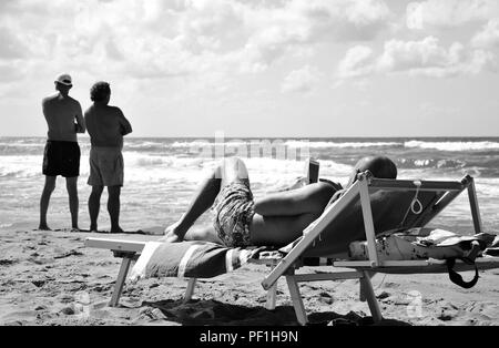 Deux types de la contemplation de notre ère technologique. Un seul homme contemple son smartphone pendant que deux amis contempler la mer infinie. Sabaudia Banque D'Images