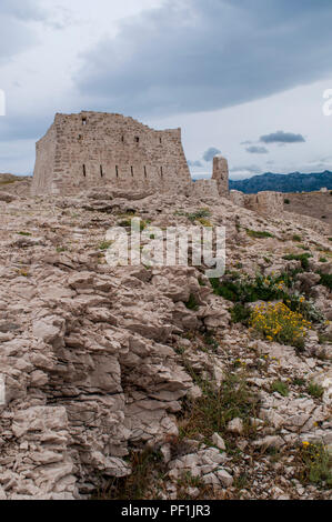 Croatie : temps orageux et vue sur la tour de guet en ruine en face de Paški Most, le pont 1968 qui relie la terre ferme et l'île de Pag Banque D'Images