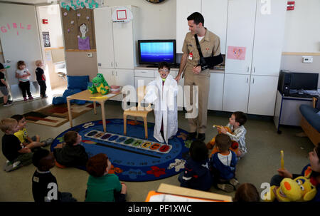 Le Lieutenant Matthew Jurcak, un dentiste avec le 1er Bataillon dentaire, 1er Groupe logistique maritime, un enfant permet de porter son manteau de dentiste au San Onofre Centre pour le développement de l'enfant lors d'un programme de sensibilisation de la santé dentaire à bord de Camp Pendleton, en Californie, le 23 février 2016. Bn dentaire. a été aux écoles et centres de développement de l'enfant autour de Camp Pendleton durant le mois de février pour le mois de la santé dentaire des enfants d'enseigner de bonnes habitudes d'hygiène buccale et de promouvoir la santé dentaire. (U.S. Marine Corps photo par le Cpl. Carson Gramley/libérés) Banque D'Images