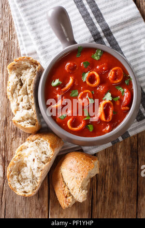 Soupe de tomate épaisse italienne avec des calmars close-up dans un bol, servi avec du pain. vertical haut Vue de dessus Banque D'Images