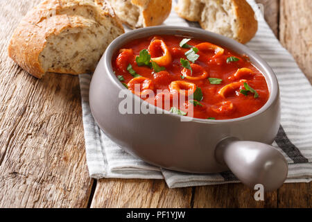 La nourriture italienne maison squid braisé en sauce tomate avec des épices et persil close-up dans un pot, et de pain frais. Banque D'Images