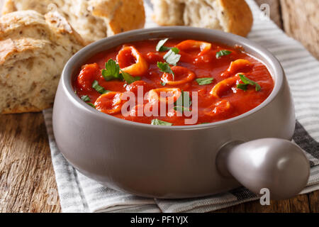 Fruits de mer méditerranéens traditionnels anneaux de calmars de la tomate avec des épices et persil close-up dans un pot et de pain frais. Banque D'Images