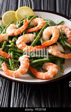 L'alimentation saine : grosses crevettes avec haricots verts, fromage et citron gros plan sur une plaque verticale sur la table. Banque D'Images