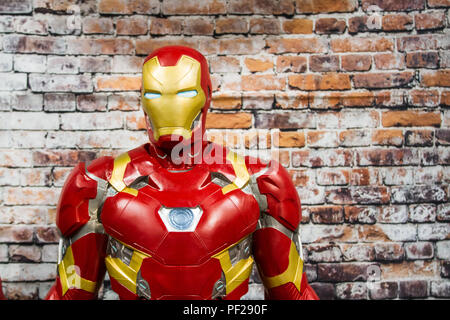 Un mâle cosplayeuse habillée en homme de fer de Marvel comics la franchise film debout devant un mur de briques avec copie espace. Banque D'Images