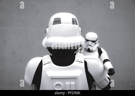 Un homme vêtu comme un cosplayeur Stormtrooper de la franchise Star Wars Stormtrooper holding a toy soigneusement dans un drôle de père et fils de droit. Banque D'Images