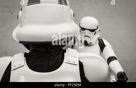 Un homme vêtu comme un cosplayeur Stormtrooper de la franchise Star Wars Stormtrooper holding a toy soigneusement dans un drôle de père et fils de droit. Banque D'Images