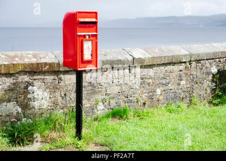 Post box rouge écossais en zone rurale très éclairé sous ciel noir Banque D'Images