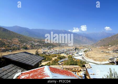 Piment rouge séchage sur toit de style traditionnel bhoutanais maisons avec vue sur la ville de Thimphu près de la rivière à Paro, Bhoutan Banque D'Images