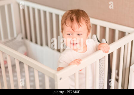 Cute little baby boy looking out de son lit dans sa chambre Banque D'Images