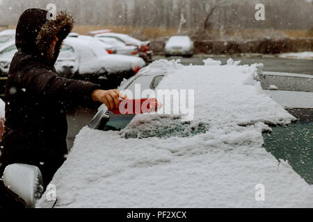 Après une tempête de neige à pelleter et enlever la neige femme de sa voiture, la neige bloque Banque D'Images