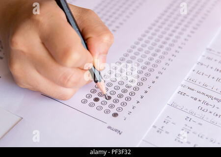 Les élèves hand holding crayon écrivant certains choix sur les feuilles de réponses et mathématiques question feuilles. Les élèves faisant des tests d'examen. examen scolaire Banque D'Images