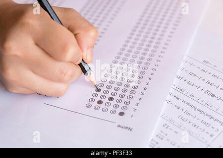 Les élèves hand holding crayon écrivant certains choix sur les feuilles de réponses et mathématiques question feuilles. Les élèves faisant des tests d'examen. examen scolaire Banque D'Images